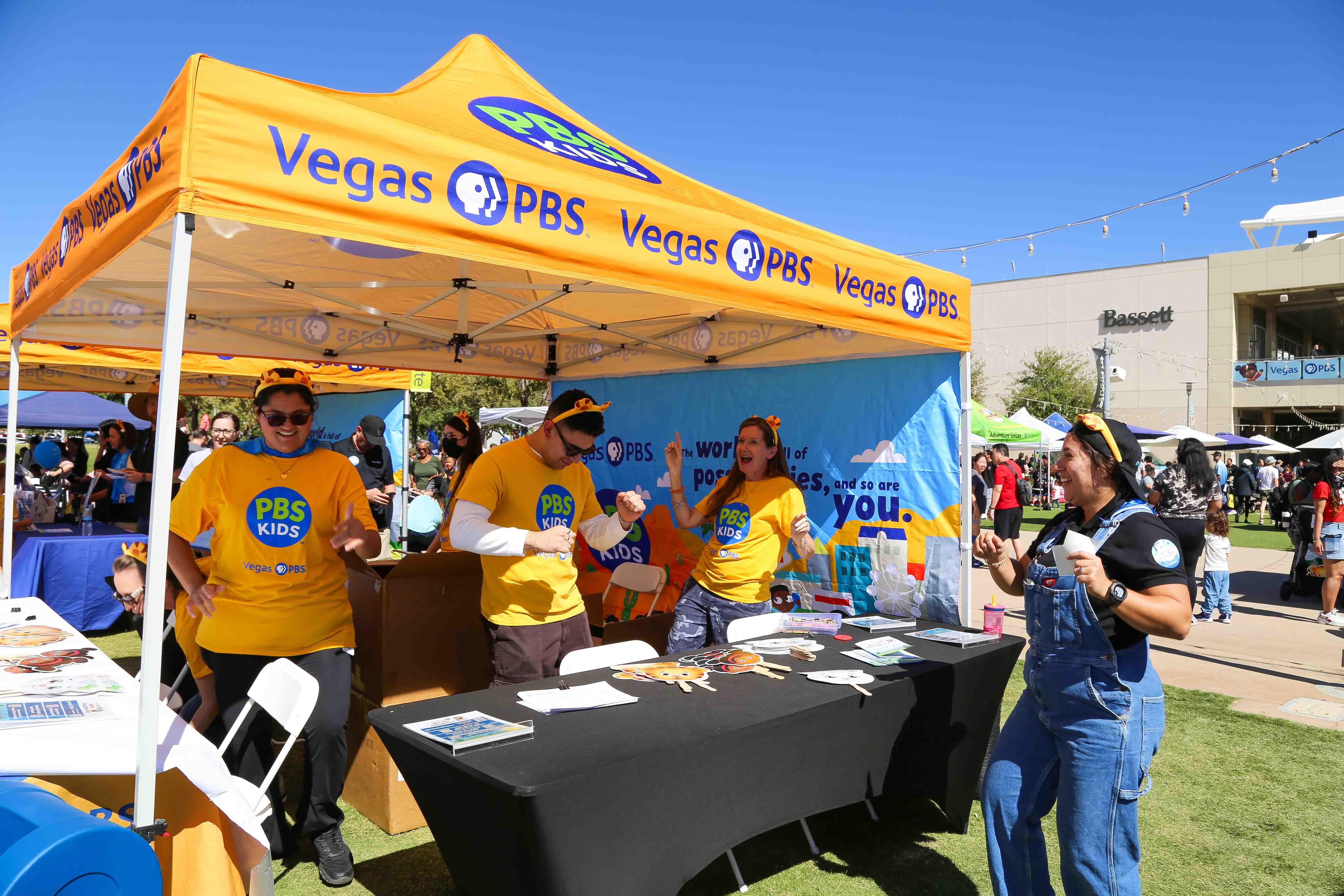 Yellow Vegas PBS tent with volunteers manning a table