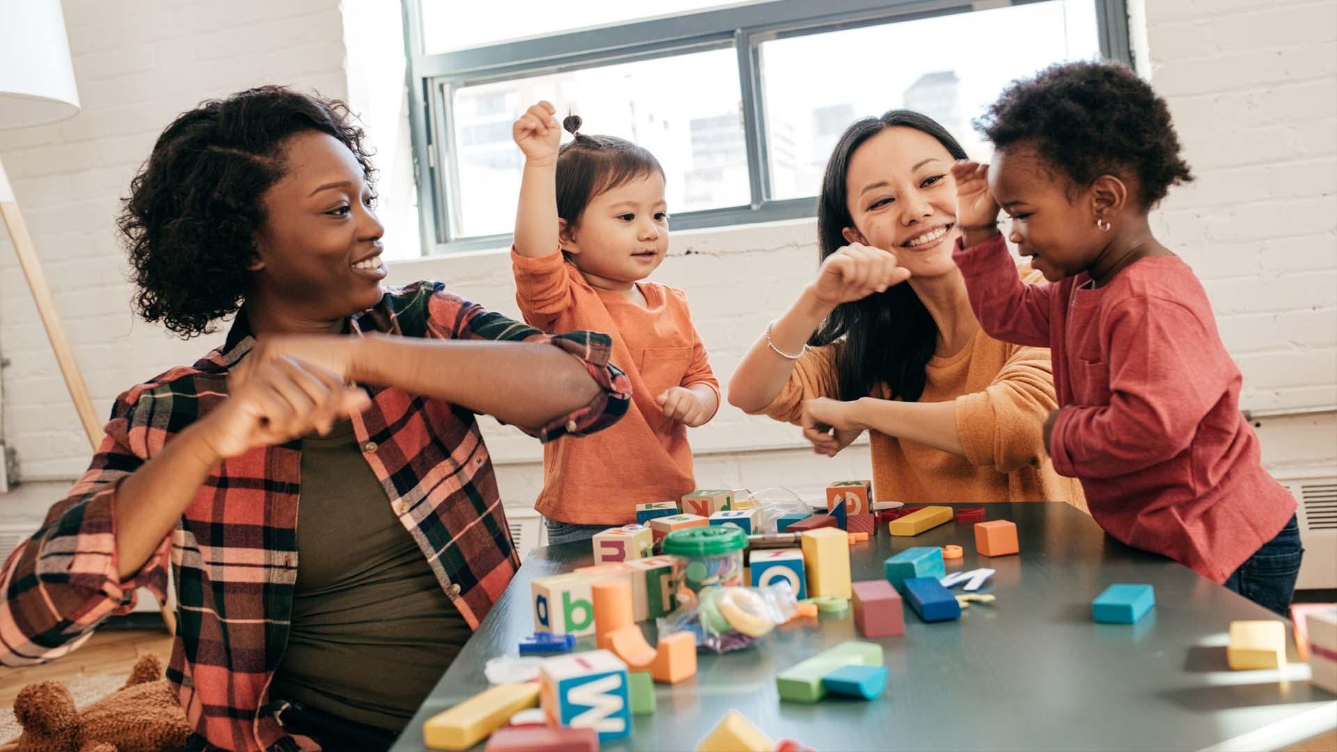 Moms and small children playing at a table