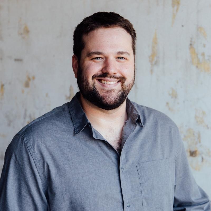 An image of Forrest Mason in a grey button-down shirt.