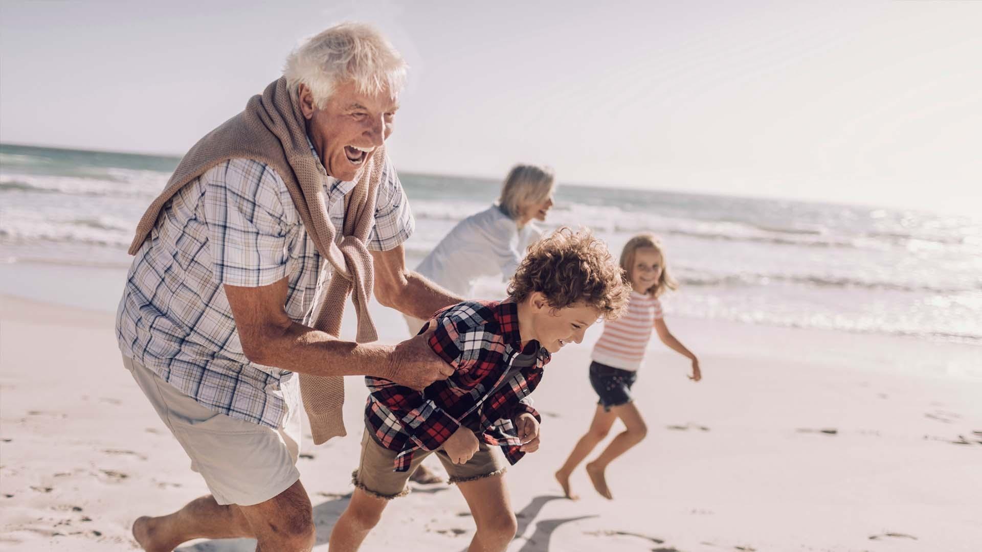 grandparents and children playing happily on the beachh
